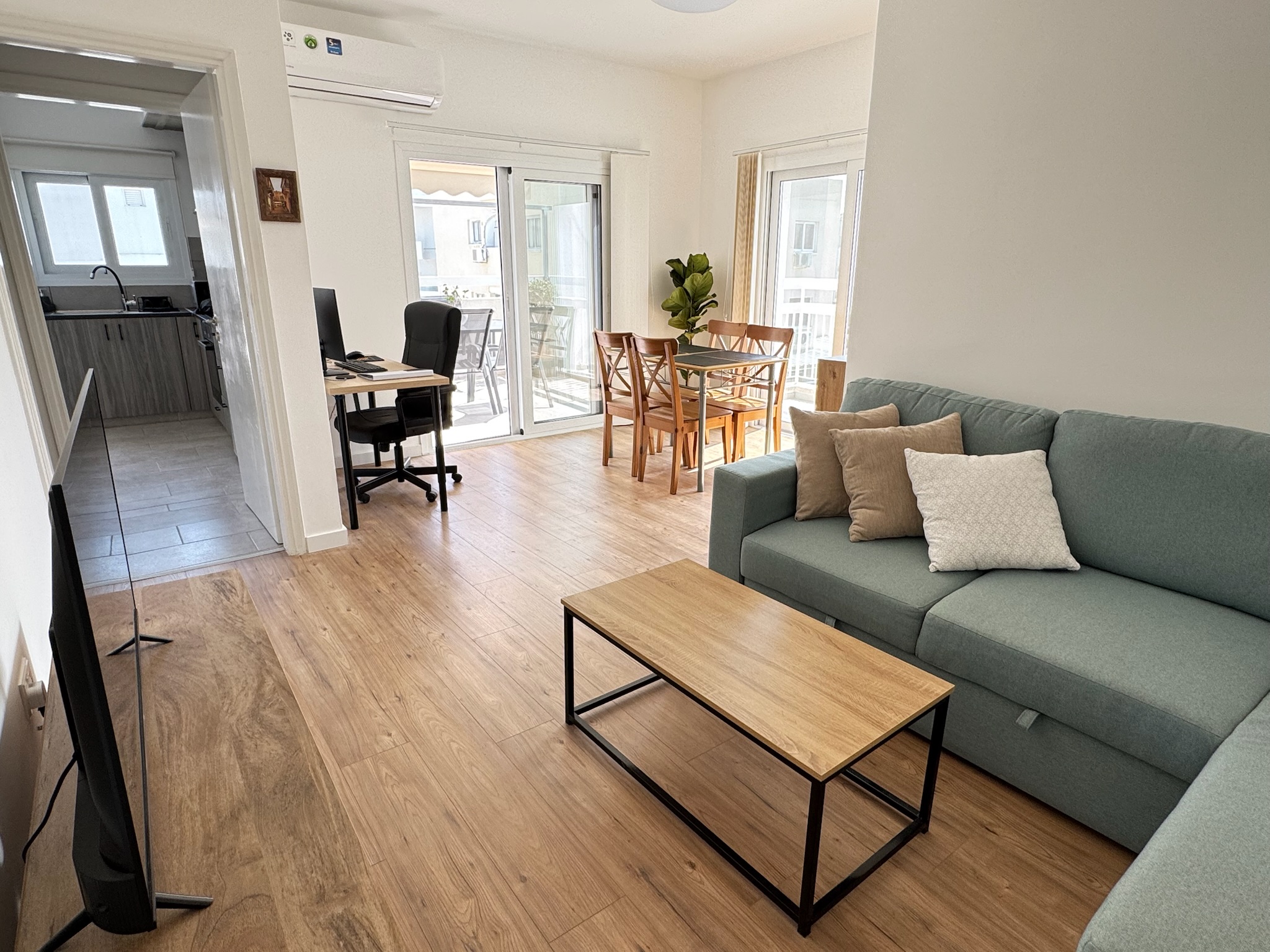 Living room with sofa, dining area, kitchen access and workstation area at Nicosia Business Apartment